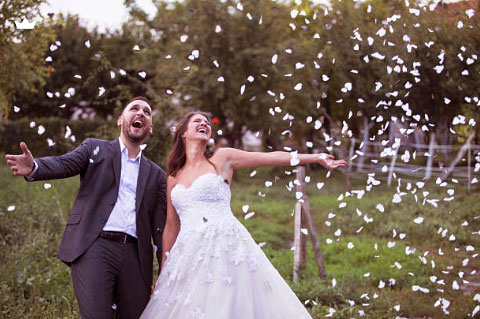 A bride and groom celebrating joyfully under falling confetti, showing the happiness of getting precious memories saved by a wedding photo retouching service UK.