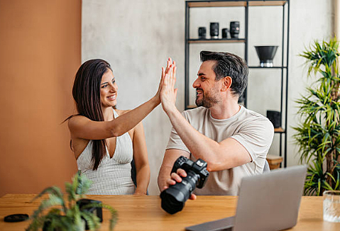 Photographer and retoucher celebrating successful outsourced photo retouching collaboration